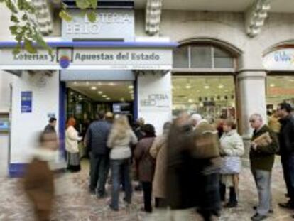 Varias personas esperan su turno fuera de una administraci&oacute;n de loter&iacute;a en Valencia.