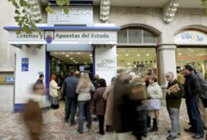 Varias personas esperan su turno fuera de una administración de lotería en Valencia.