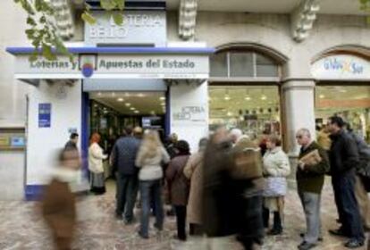 Varias personas esperan su turno fuera de una administraci&oacute;n de loter&iacute;a en Valencia.