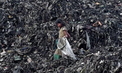 Una niña busca entre la basura de un vertedero en Guwahati, (India).