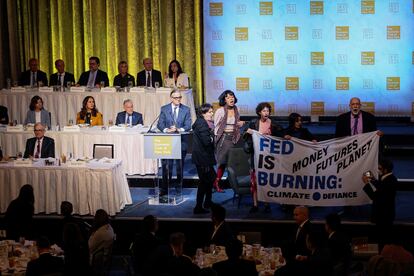 Activistas climáticos interrumpen la reunión del Club Económico de Nueva York en la que ha intervenido el presidente de la Reserva Federal, Jerome Powell, al que se ve sentado en la mesa de la primera fila del escenario.