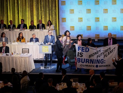 Activistas climáticos interrumpen la reunión del Club Económico de Nueva York en la que ha intervenido el presidente de la Reserva Federal, Jerome Powell, al que se ve sentado en la mesa de la primera fila del escenario.