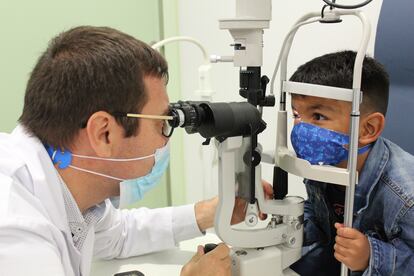 El doctor Jaume Català examina el ojo de Félix tras superar un tumor de retina en el hospital Sant Joan de Déu.