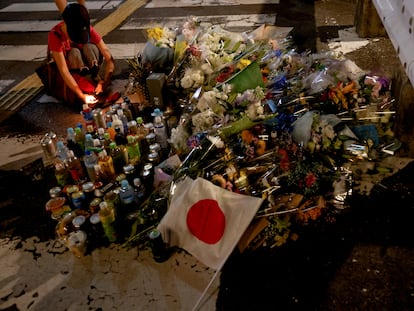 A person pays respects next to tributes laid at the site where late former Japanese Prime Minister Shinzo Abe was shot while campaigning for a parliamentary election, near Yamato-Saidaiji station in Nara, western Japan, July 8, 2022. REUTERS/Issei Kato