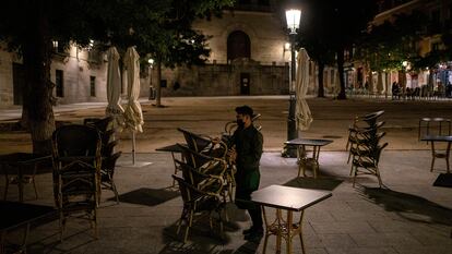 Un camarero recoge la terraza de un bar en la plaza de la Paja de Madrid.