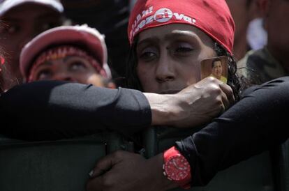Una chavista sujeta un recordatorio de Chávez mientras espera el paso del cortejo funerario hacia una academia militar en Caracas.