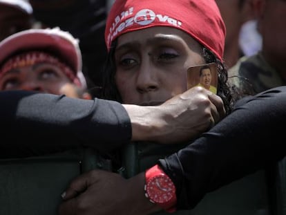 Una chavista sujeta un recordatorio de Ch&aacute;vez mientras espera el paso del cortejo funerario hacia una academia militar en Caracas. 