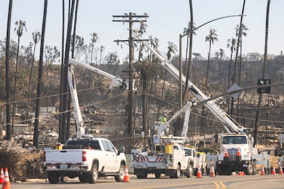 Trabajadores de la compa?a elctrica trabajan en la zona quemada en el incendio en la carretera que recorre la playa en Pacific Palisades.