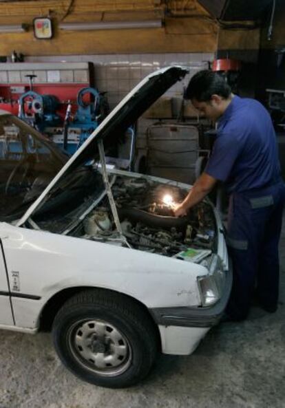 Un mecánico arregla un coche en el taller Albea de Sevilla.