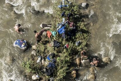 Um grupo de migrantes se refresca e lava sua roupa no riu Huixtla, a 70 quilômetros da fronteira com a Guatemala.