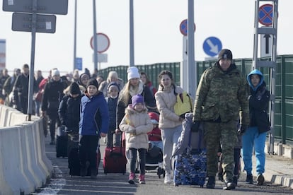 Un guardia fronterizo polaco ayuda a los refugiados ucranios a llegar a Polonia en el cruce fronterizo de Korczowa. Unas 100.000 personas han cruzado ya la frontera a Polonia desde el comienzo de la invasión rusa de Ucrania, informó hoy el viceministro del Interior polaco, Pawel Szefernaker.
