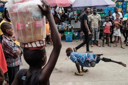 Los transeúntes observan cómo Kevin, un joven bailarín nigeriano de 18 años, discapacitado, también conocido como T-Boy, realiza una exhibición de break dance en Port Harcourt (Nigeria).