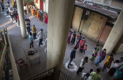 Varias personas aguardan su turno para votar en la tercera fase de las elecciones a la asamblea del Estado de Assam (India) en las marcas de distanciamiento dibujadas en el suelo como protección contra el coronavirus.