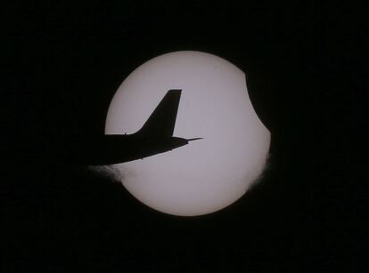 La cua d'un avió de passatgers sobrevola el cel de la ciutat filipina de Taguig durant l'eclipsi solar.