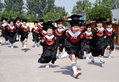 Un grupo de alumnos recién graduados corren durante la ceremonia, en un parque de Handan (China).
