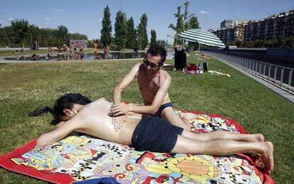 Jóvenes toman el sol en Madrid Río, 5 de julio de 2013. En la Comunidad de Madrid, que permanece en alerta amarilla por calor, seguirán subiendo las temperaturas, donde este viernes llegarán a los 38 grados en el sur.