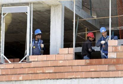 Tres obreros trabajan en una vivienda en construcci&oacute;n. 