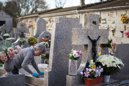 Una mujer limpia la tumba de un familiar en el cementerio de Manzanares el Real, en Madrid. 