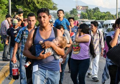 Un hombre carga con su hijo en brazos desde San Pedro Sula, 180 km al norte de Tegucigalpa, el 13 de octubre de 2018. 