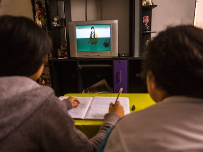 Dos niñas peruanas estudiando frente a la televisión durante la pandemia.