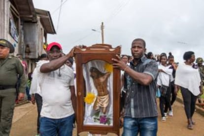 Supervivientes de la masacre de Bojayá transportan lo que queda del Cristo de su iglesia.