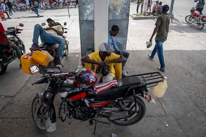 Pessoas ficam de guarda enquanto esperam combustível em um posto fechado em Porto Príncipe. 