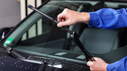 Un hombre cambiando las escobillas en su coche.