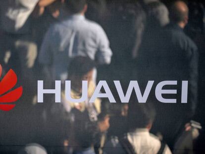 Varias personas se reflejan en un espejo con un logotipo de Huawei. 