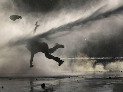 Una manifestante recibe el golpe de un chorro de agua durante una manifestación de protesta realizada en Santiago el 9 de diciembre.