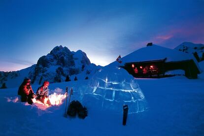 Los tradicionales iglús (del inuit 'casa') se convierten en bares, restaurantes, habitaciones de hotel o lo que haga falta en los centros de nieve. En la fotografía, noche junto a una de estas construcciones de bloques de nieve en la estación de esquí suiza de Gstaad, con el imponente perfil del monte Gummfluh (2.458 metros de altura) al fondo.