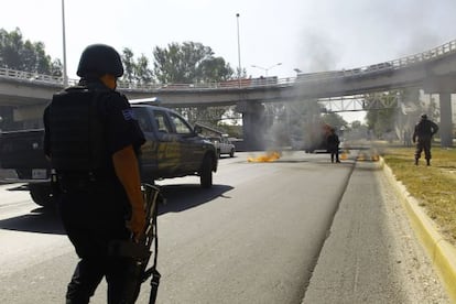 Bomberos y policía estatal apagan uno de los vehículos incendiados.