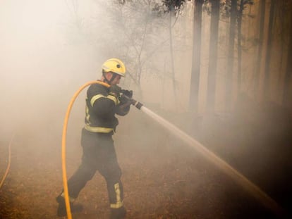 Un bombero trabaja este domingo en el incendio de Pazos de Bord&eacute;n (Pontevedra).