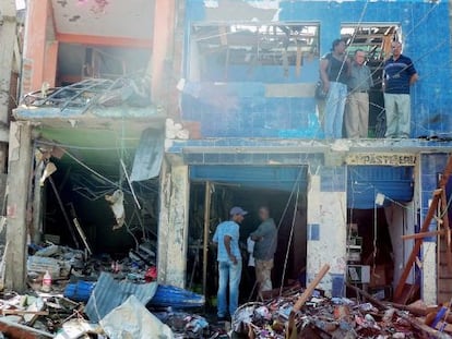 Un grupo observa los destrozos que caus&oacute; la bomba.