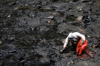 Un trabajador limpia la playa de Ventanilla, en Perú, este martes. Las autoridades estiman que el crudo afecta a unos 18.000 kilómetros cuadrados en el mar. El ministro de Ambiente, Rubén Ramírez, aseguró que el derrame sería de 6.000 barriles de petróleo.