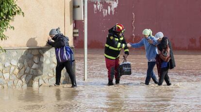 Un militar de la Unidad Militar de Emergencia (UME) ayuda a varias mujeres a cruzar una calle inundada en Los Alcázares, Murcia, el 19 de diciembre de 2016.