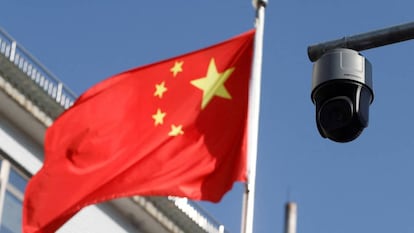FILE PHOTO: A security surveillance camera overlooking a street is pictured next to a nearby fluttering flag of China in Beijing, China November 25, 2021. Picture taken November 25, 2021. REUTERS/Carlos Garcia Rawlins/File Photo