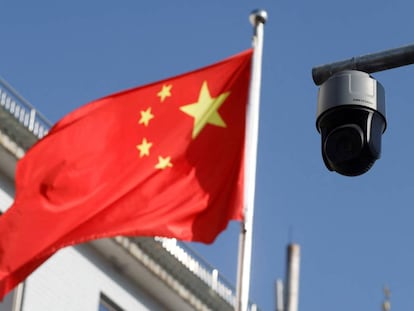 FILE PHOTO: A security surveillance camera overlooking a street is pictured next to a nearby fluttering flag of China in Beijing, China November 25, 2021. Picture taken November 25, 2021. REUTERS/Carlos Garcia Rawlins/File Photo