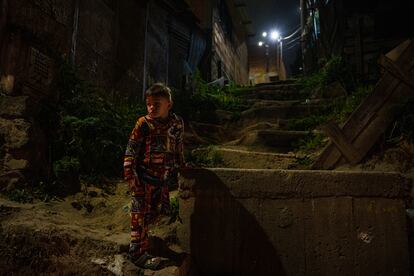 Un niño en las empinadas escaleras que suben entre las casas del barrio.