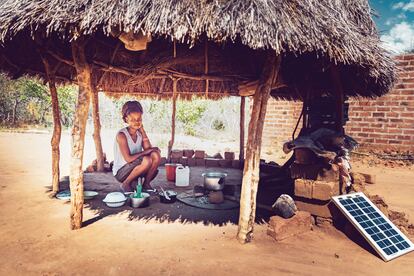 Una joven africana cocina junto a una placa solar.