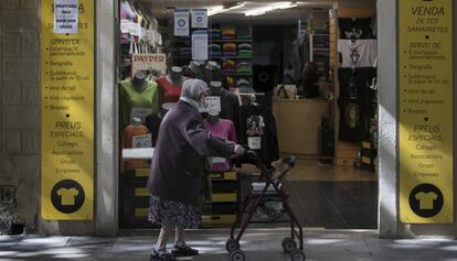 Una dona mira l'aparador d'una botiga del carrer Gran de Sant Andreu.
