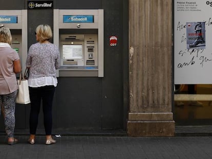 Clientes sacan dinero de un cajero.