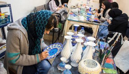 Azin en la cooperativa Tolou' de Isfahán (Teherán), en la que trabaja junto con otras mujeres, en el momento de esmaltar un plato.