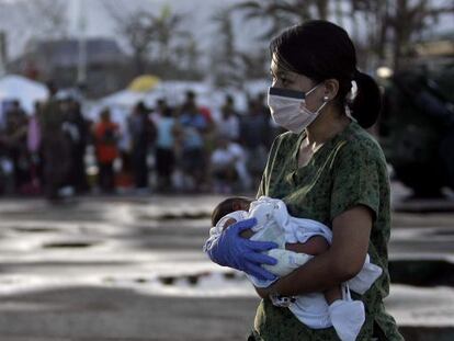 Una enfermera lleva en brazos a un bebé de siete días para evacuarlo 