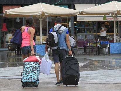 Unos turistas caminan con sus maletas por el barrio de La Barceloneta. 
