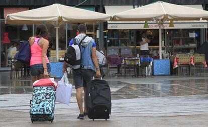 Unos turistas caminan con sus maletas por el barrio de La Barceloneta.