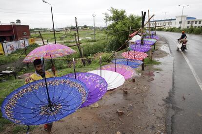 Un comerciante coloca paraguas junto a una carretera para su venta durante un día lluvioso en Amristar (India).