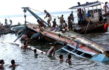 Pescadores locales colaboran en el rescate del barco que ha naufragado en un ro de India.