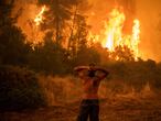 A local resident reacts as he observes a large blaze during an attempt to extinguish forest fires approaching the village of Pefki on Evia (Euboea) island, Greece's second largest island, on August 8, 2021. - Hundreds of Greek firefighters fought desperately on August 8 to control wildfires on the island of Evia that have charred vast areas of pine forest, destroyed homes and forced tourists and locals to flee. Greece and Turkey have been battling devastating fires for nearly two weeks as the region suffered its worst heatwave in decades, which experts have linked to climate change. (Photo by ANGELOS TZORTZINIS / AFP)