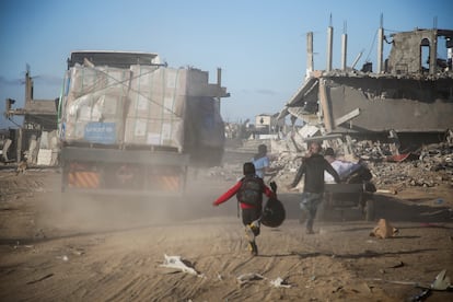 Diverse persone rincorrono camion che trasportano aiuti umanitari, questo lunedì a Rafah. 