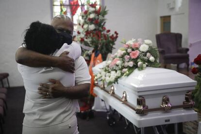 Duas pessoas abraçam-se em um funeral de uma mulher falecida por covid em Los Angeles.